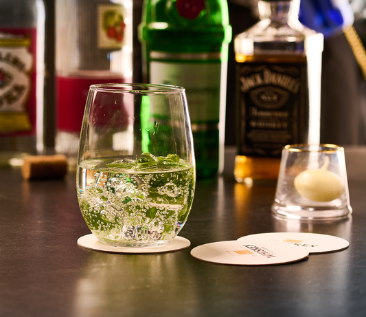 A glass placed on a personalized custom printed coaster at a bar